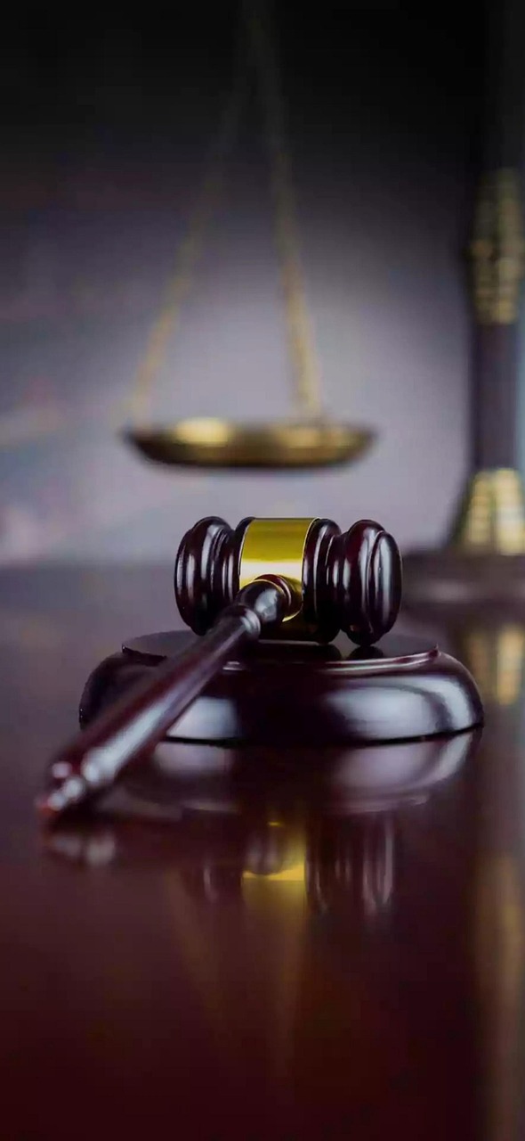 Wooden gavel and brass scales on dark surface